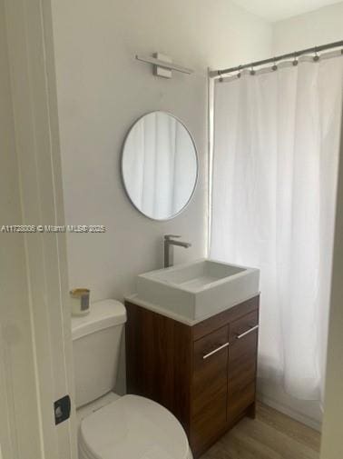 bathroom with hardwood / wood-style flooring, curtained shower, toilet, and vanity