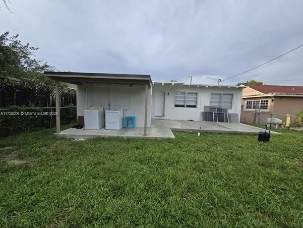 rear view of property featuring a patio, a yard, and washing machine and clothes dryer