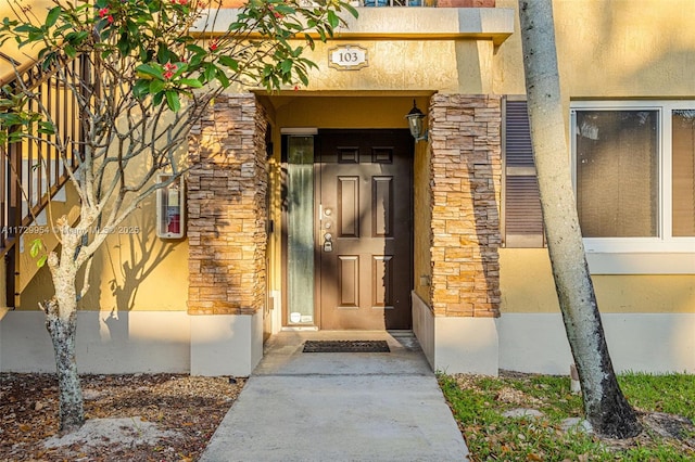 entrance to property featuring stone siding and stucco siding