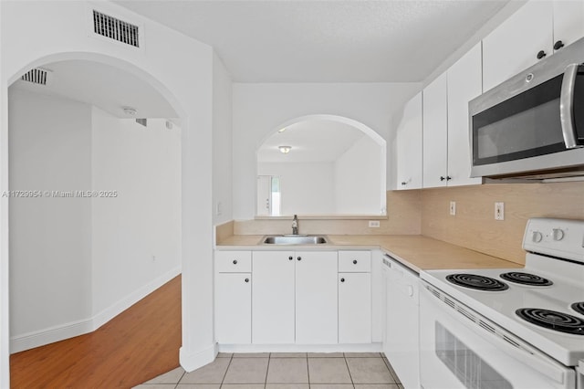 kitchen featuring white appliances, visible vents, a sink, light countertops, and white cabinetry