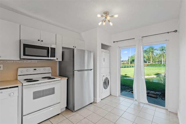 kitchen featuring stacked washing maching and dryer, appliances with stainless steel finishes, light tile patterned flooring, white cabinets, and light countertops