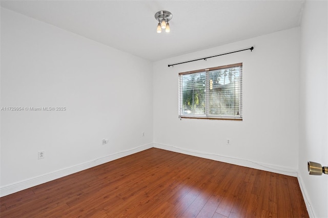 spare room with hardwood / wood-style floors and baseboards