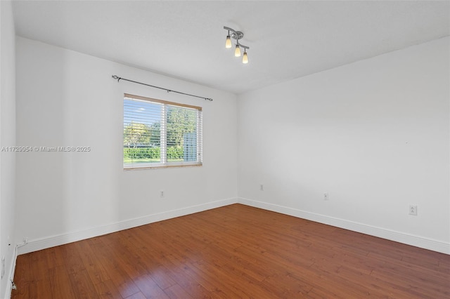 unfurnished room with hardwood / wood-style flooring and baseboards