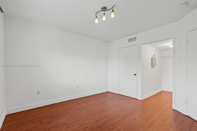 empty room featuring visible vents, baseboards, and wood finished floors