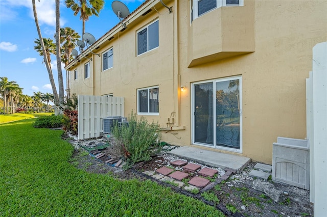 back of property featuring central air condition unit, a yard, and stucco siding