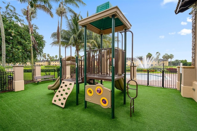 community play area with a yard, a water view, and fence