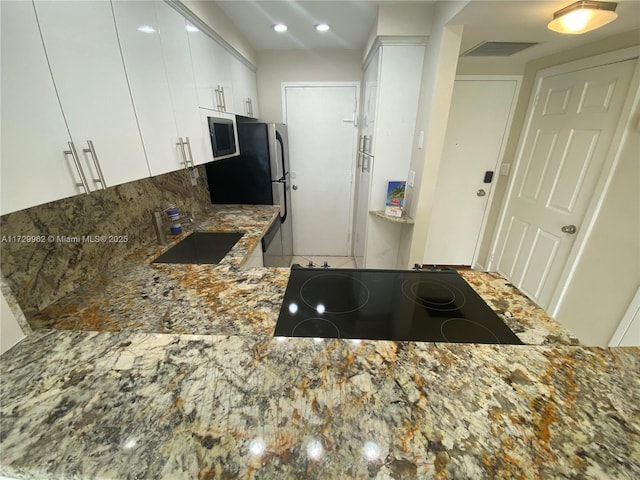 kitchen featuring white cabinets, stainless steel appliances, sink, kitchen peninsula, and stone counters