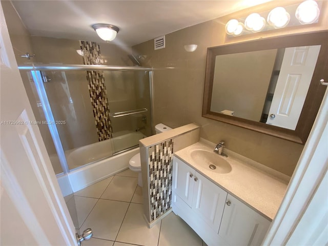 full bathroom featuring combined bath / shower with glass door, vanity, toilet, and tile patterned flooring