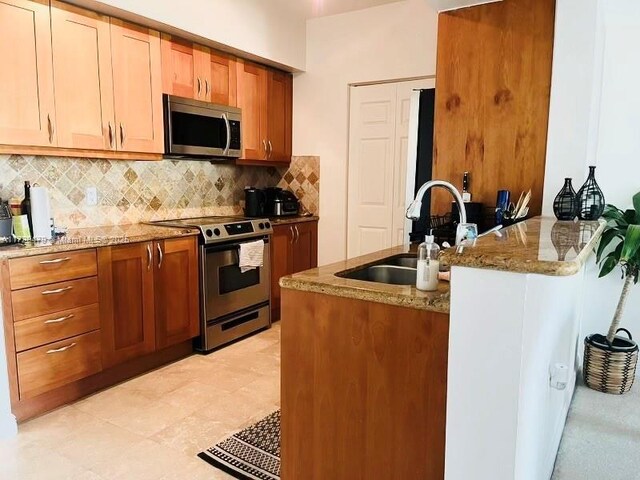 1755 E Hallandale Beach Blvd Unit 1605E, Hallandale Beach, FL 33009 - kitchen with stainless steel appliances, a sink, decorative backsplash, and stone counters