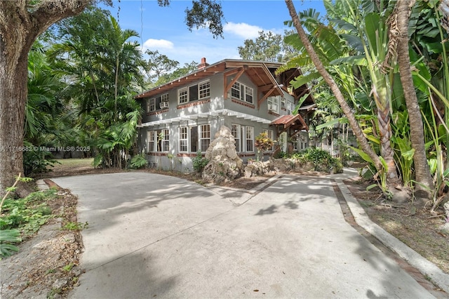 view of front of home featuring concrete driveway, a chimney, and stucco siding