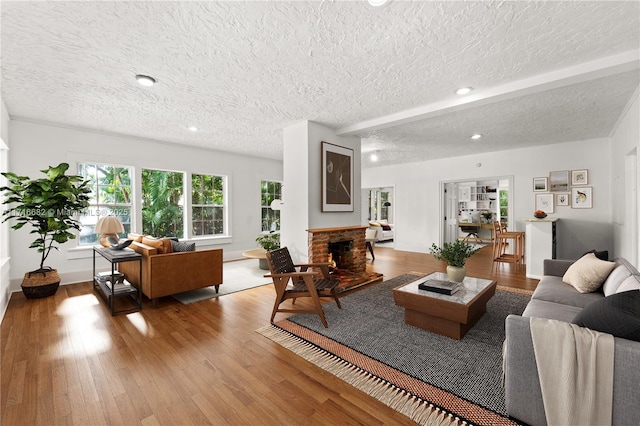 living area with a textured ceiling, a fireplace, wood finished floors, and recessed lighting