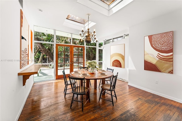 dining space with an inviting chandelier, a skylight, dark hardwood / wood-style floors, expansive windows, and french doors