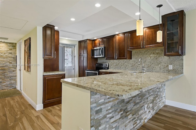 kitchen with decorative light fixtures, sink, appliances with stainless steel finishes, and kitchen peninsula