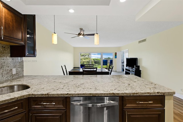 kitchen featuring decorative backsplash, light stone counters, hanging light fixtures, and stainless steel dishwasher