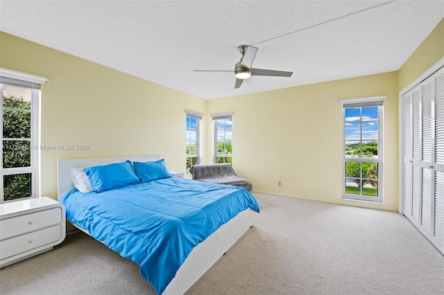 carpeted bedroom with a closet, ceiling fan, and a textured ceiling