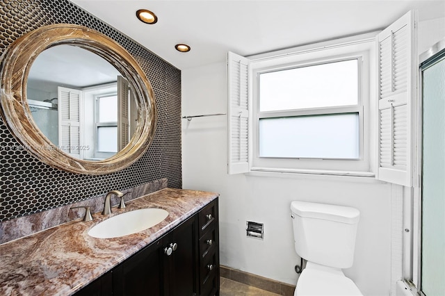 bathroom featuring a shower with shower door, toilet, and vanity