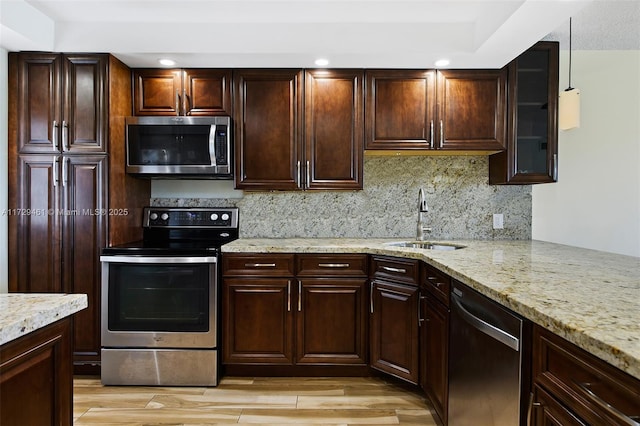 kitchen featuring sink, light wood-type flooring, light stone counters, and appliances with stainless steel finishes