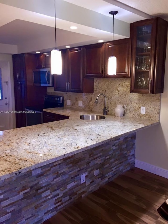 kitchen featuring light stone countertops, decorative light fixtures, dark wood-type flooring, sink, and backsplash