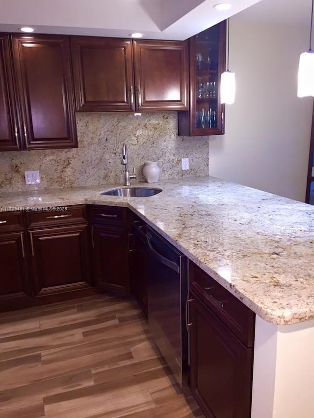 kitchen with black dishwasher, tasteful backsplash, hardwood / wood-style flooring, hanging light fixtures, and sink