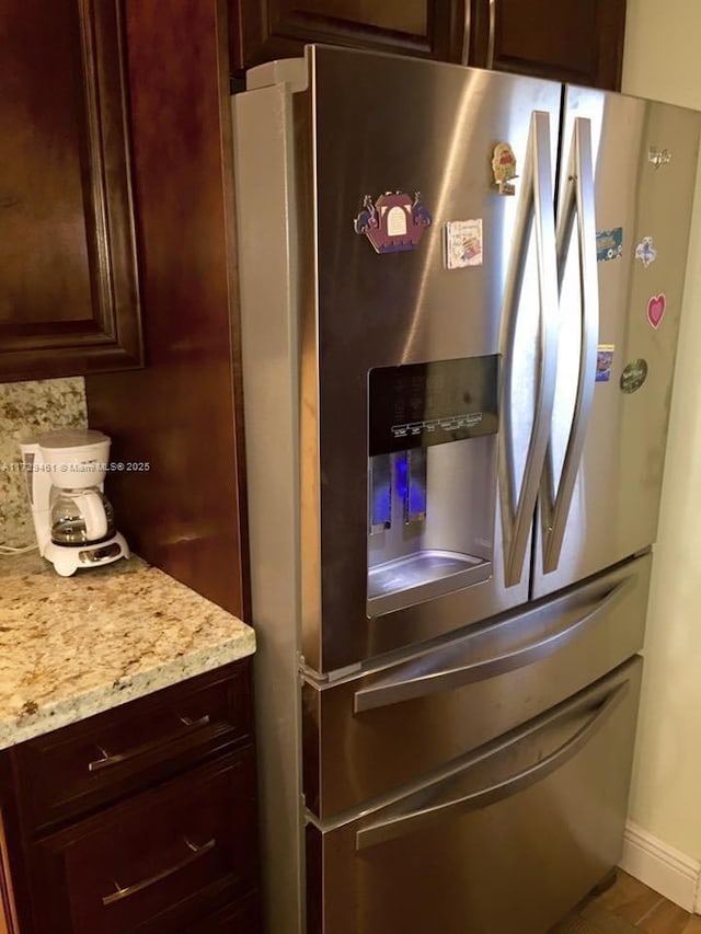 room details featuring stainless steel fridge with ice dispenser, light stone countertops, and decorative backsplash