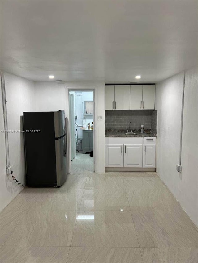 kitchen with white cabinetry, stainless steel fridge, sink, and decorative backsplash