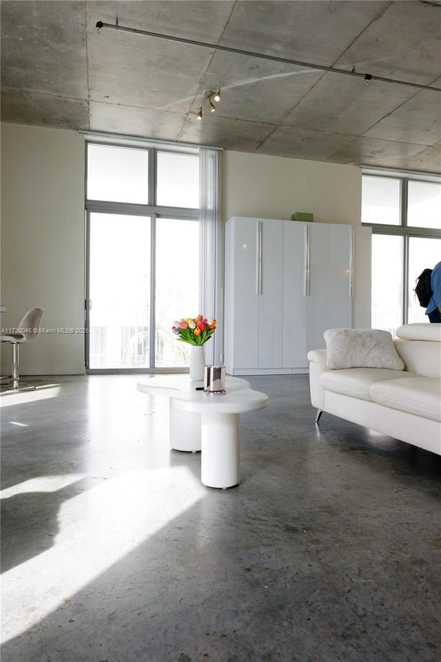 unfurnished living room featuring floor to ceiling windows, a healthy amount of sunlight, and concrete floors