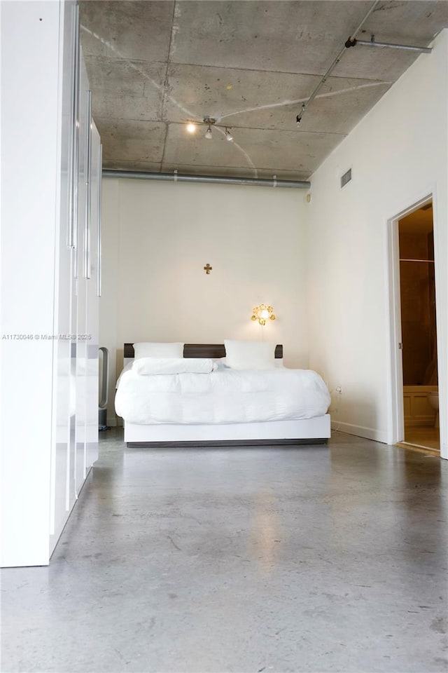 unfurnished bedroom featuring ensuite bath and concrete floors