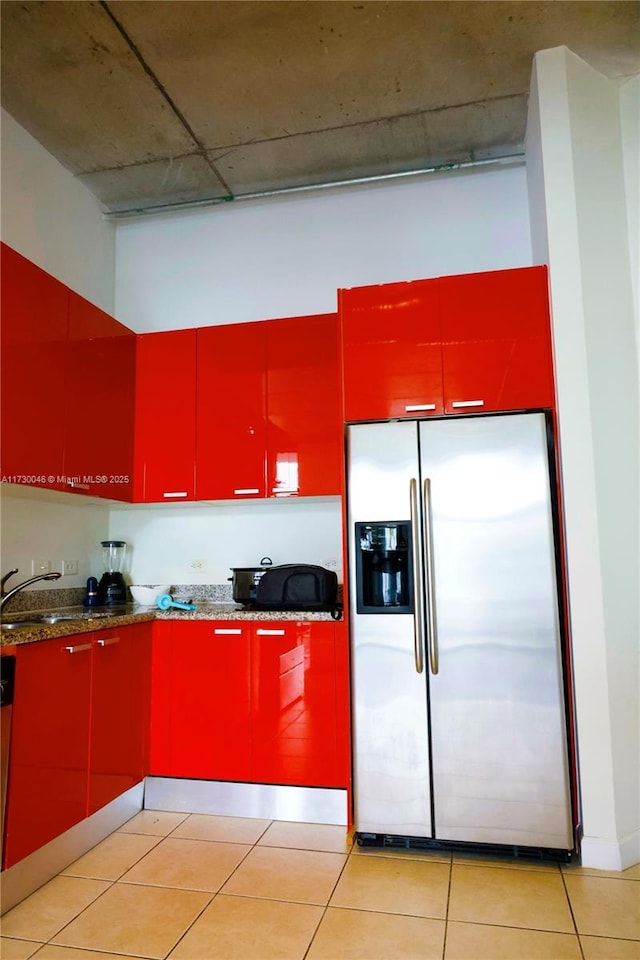 kitchen featuring sink, light tile patterned floors, and stainless steel fridge