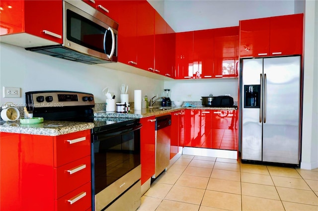 kitchen with light stone counters, stainless steel appliances, sink, and light tile patterned floors