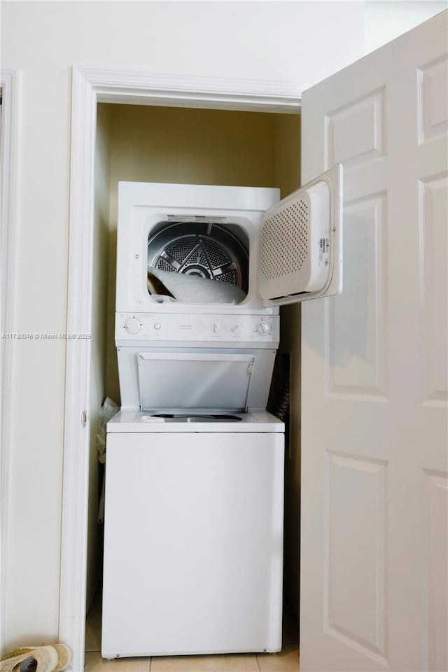 clothes washing area featuring stacked washer / dryer and light tile patterned floors