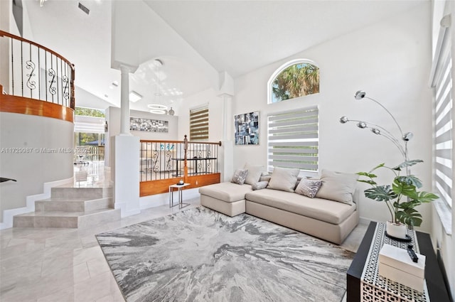 living room featuring high vaulted ceiling and decorative columns