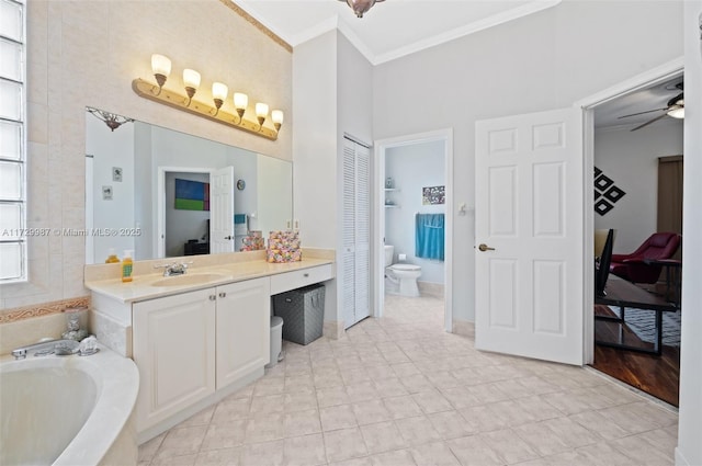 bathroom featuring ceiling fan, vanity, ornamental molding, a tub, and toilet