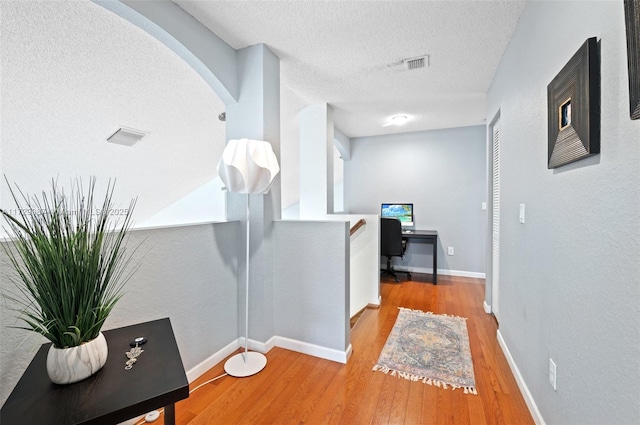 corridor featuring light hardwood / wood-style floors and a textured ceiling