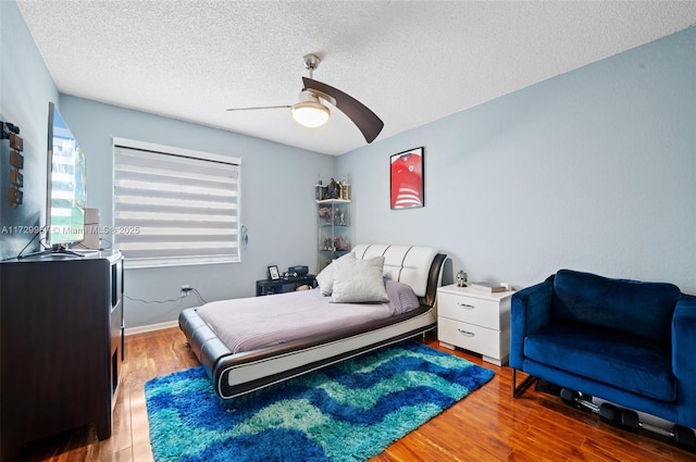 bedroom with hardwood / wood-style flooring, ceiling fan, and a textured ceiling