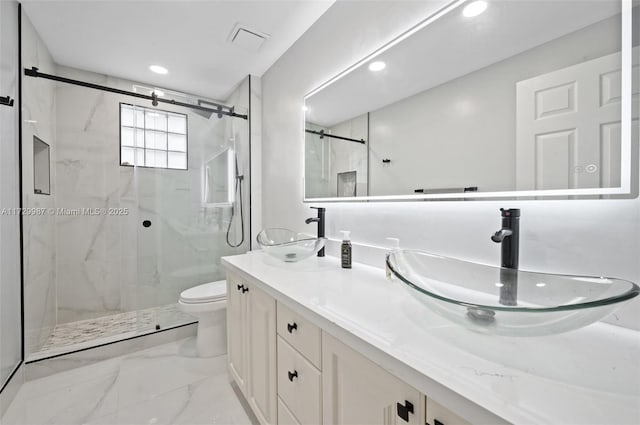 bathroom featuring a shower with door, vanity, and toilet