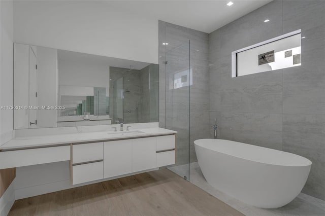 bathroom featuring wood-type flooring, vanity, and plus walk in shower