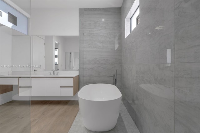 bathroom with a washtub, tile walls, vanity, and hardwood / wood-style floors