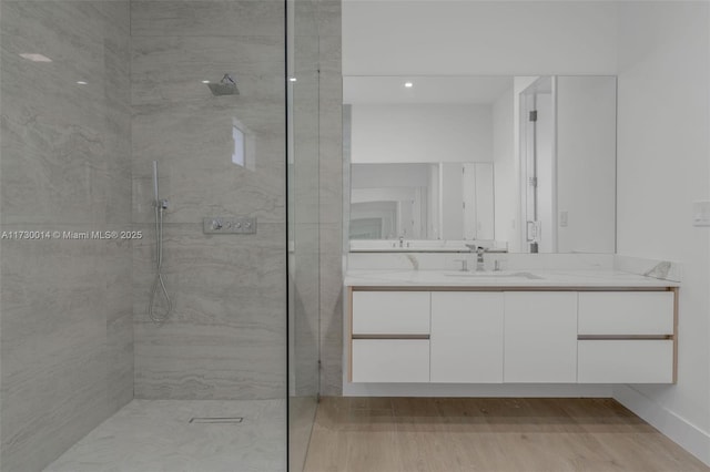 bathroom with a tile shower, hardwood / wood-style flooring, and vanity