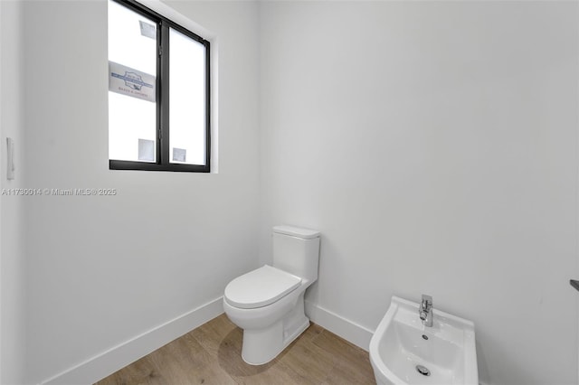 bathroom with wood-type flooring, toilet, and a bidet