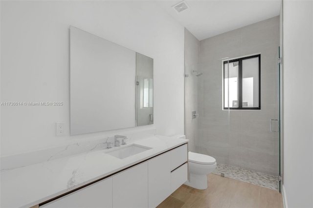 bathroom featuring a shower with door, hardwood / wood-style flooring, toilet, and vanity