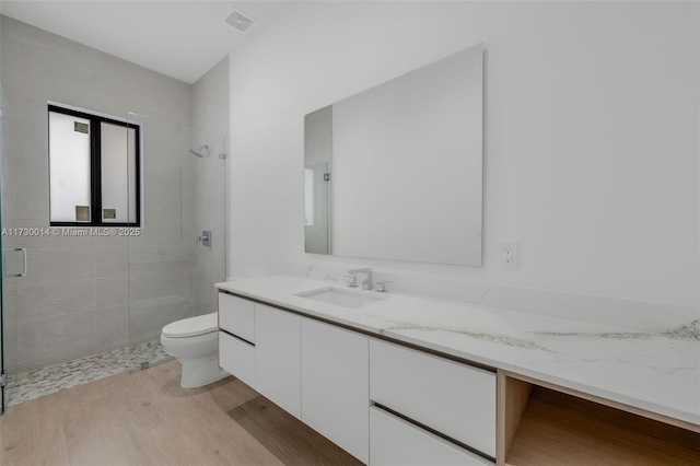 bathroom with wood-type flooring, toilet, vanity, and an enclosed shower