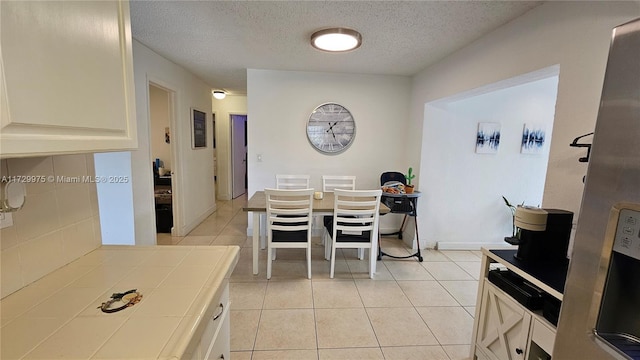 dining space featuring light tile patterned flooring, a textured ceiling, and baseboards