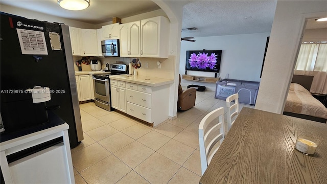 kitchen featuring light tile patterned floors, a ceiling fan, appliances with stainless steel finishes, light countertops, and a textured ceiling