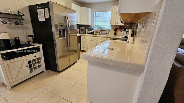 kitchen with tile countertops, light tile patterned floors, stove, a sink, and stainless steel fridge with ice dispenser