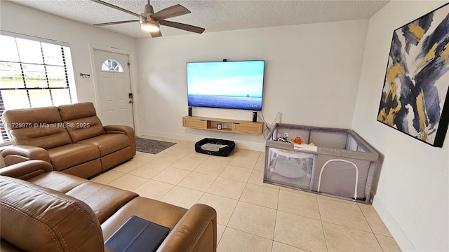 tiled living area featuring a textured ceiling, ceiling fan, and baseboards