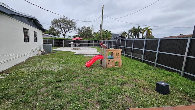 view of yard featuring a playground, central AC, a patio area, and a fenced backyard