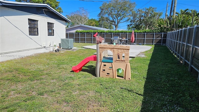 view of play area with central AC unit, a lawn, and a fenced backyard