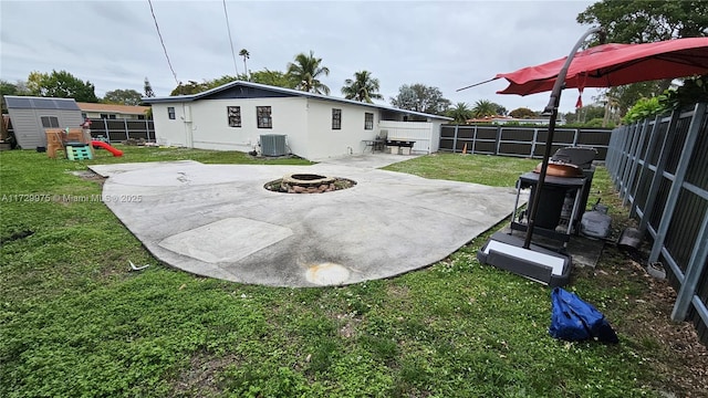 back of house with a fire pit, a yard, a patio area, central AC, and a playground