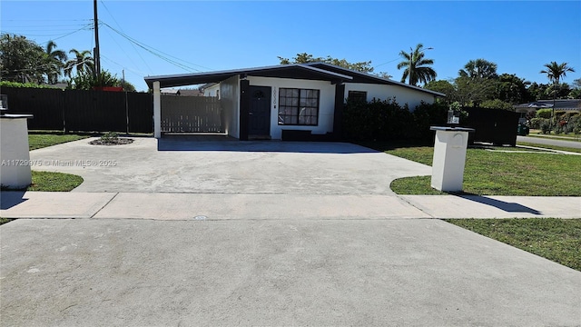 view of front of house featuring driveway, stucco siding, fence, and a front yard