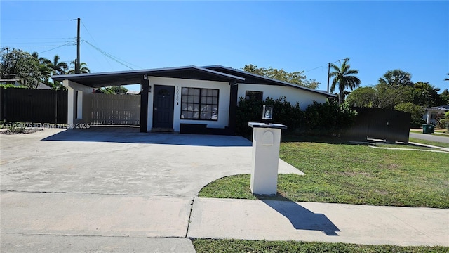 view of front of house with a carport, fence, concrete driveway, and a front yard